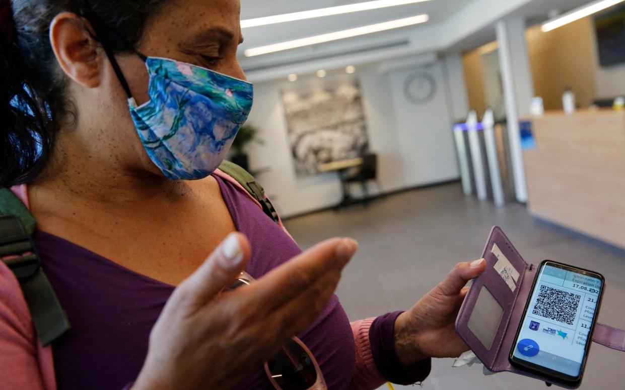 A woman shows her 'green pass', providing proof that she has been fully vaccinated against Covid, before she enters a gym in the Israeli city of Tel Aviv - Gil Cohen-Magen/ AFP