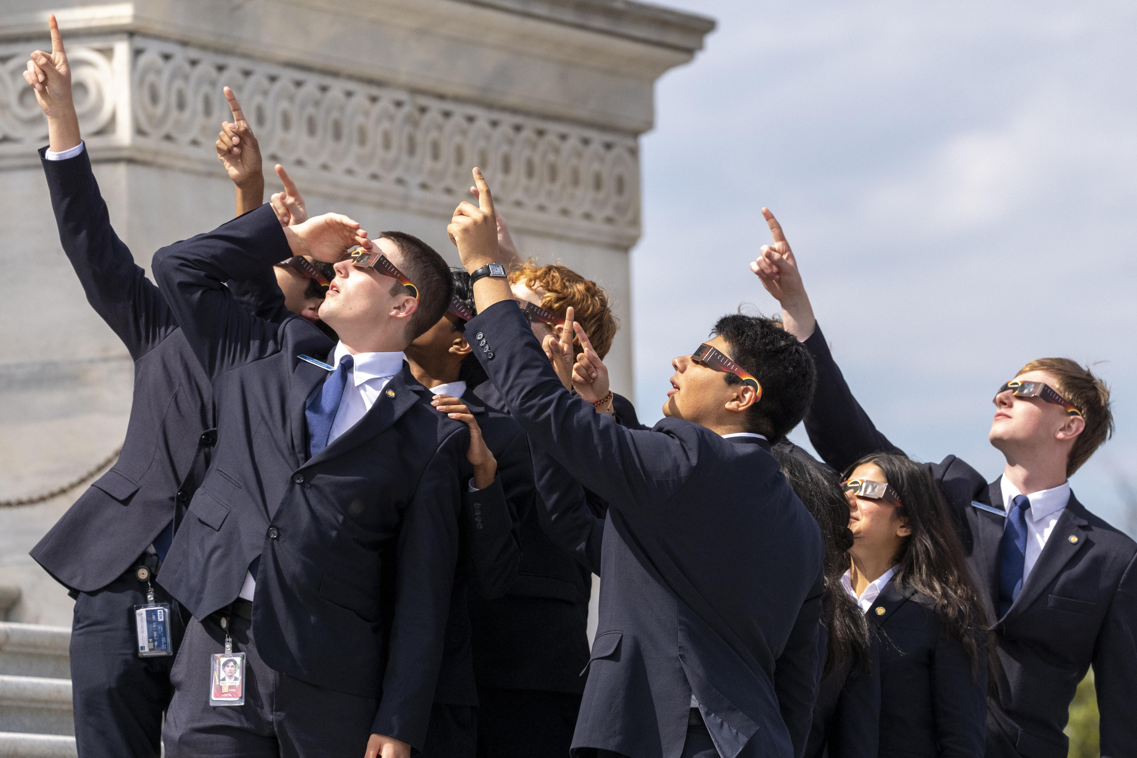 Senate pages wear eclipse glasses as they view the moon partially covering the sun during a total solar eclipse, in front of the U.S. Senate on Capitol Hill, Monday, April 8, 2024, in Washington. (Alex Brandon/AP)