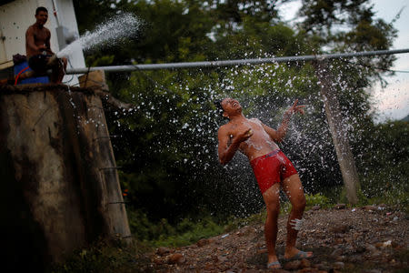 A migrant, part of a caravan of thousands traveling from Central America en route to the United States, takes a shower in Santiago Niltepec, Mexico, October 29, 2018. REUTERS/Ueslei Marcelino