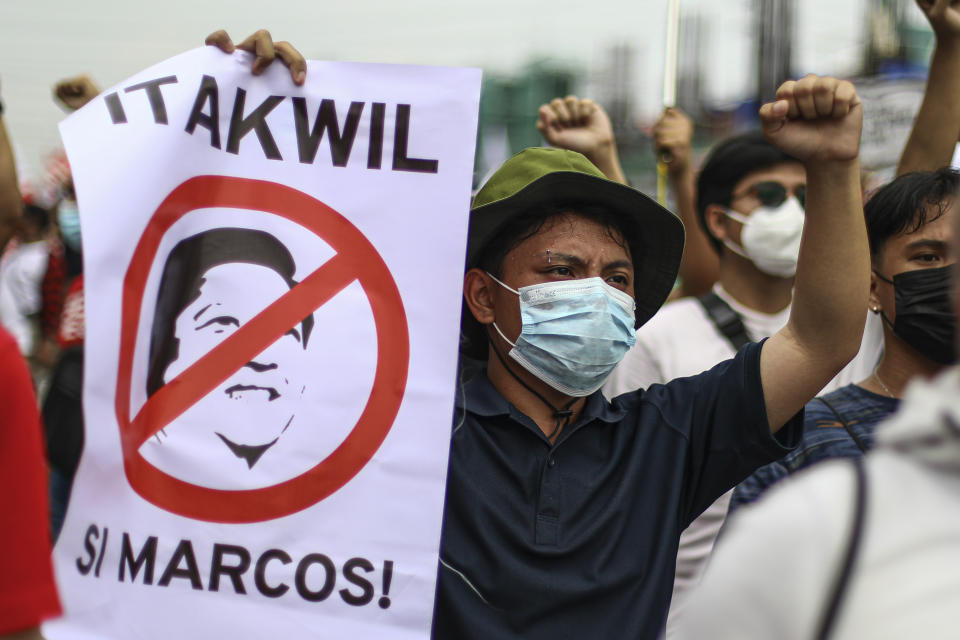 A protester clenches his fist as he carries a placard that reads "Reject Marcos" during a rally against the State of the Nation address in Quezon City, Philippines Monday, July 25, 2022. Philippine President Ferdinand Marcos Jr. will deliver his first State of the Nation address Monday with momentum from his landslide election victory, but he's hamstrung by history as an ousted dictator’s son and daunting economic headwinds. (AP Photo/Gerard Carreon)
