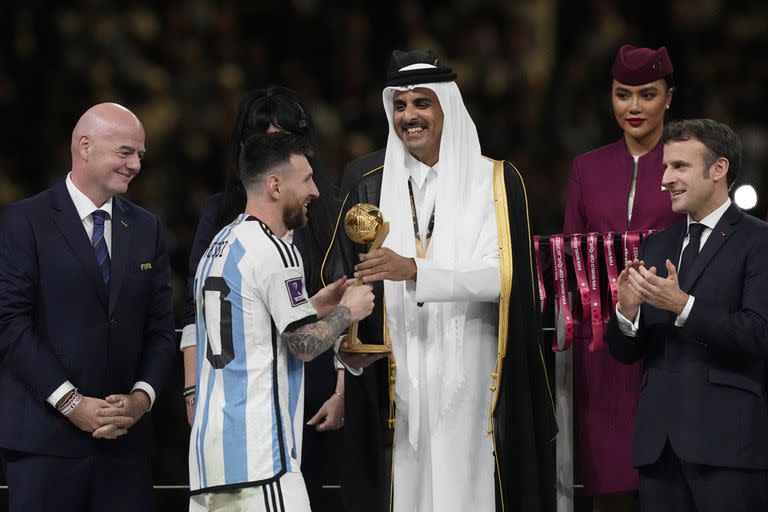 El emir de Qatar, el jeque Tamim bin Hamad Al Thani, entrega al argentino Lionel Messi el Balón de Oro al mejor jugador del torneo, mientras el presidente de Francia, Emmanuel Macron, a la derecha, aplaude, al final del partido de la final de la Copa del Mundo de fútbol entre Argentina y Francia en el estadio Lusail en Lusail, Qatar, el domingo 18 de diciembre de 2022.