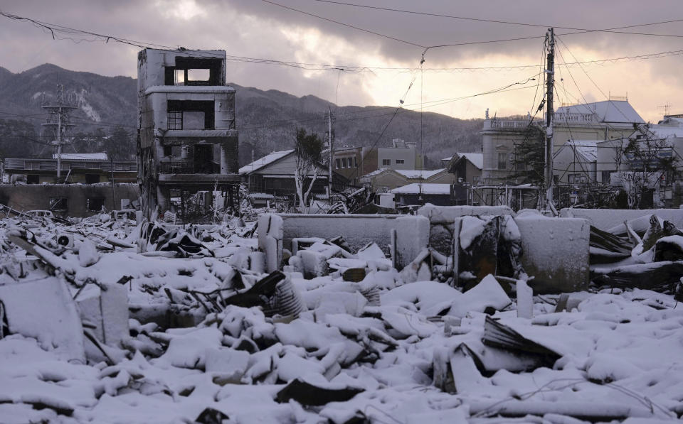 Rubble is snow-covered at a marketplace after a large fire in the earthquake-hit city, Wajima, Ishikawa prefecture, Monday, Jan. 8, 2024. Thousands of people made homeless overnight are living in weariness and uncertainty on the western coast of Japan a week after powerful earthquakes hit the region. (Kyodo News via AP)
