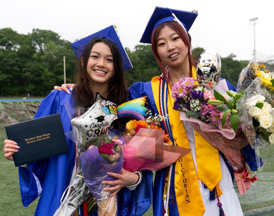 Braintree High School valedictorian May Ng, right, and a friend hold flowers and balloons.