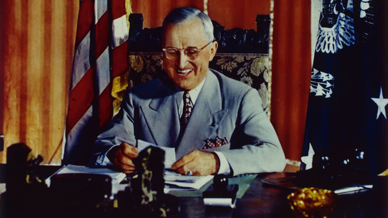 Harry Truman smiling at his desk