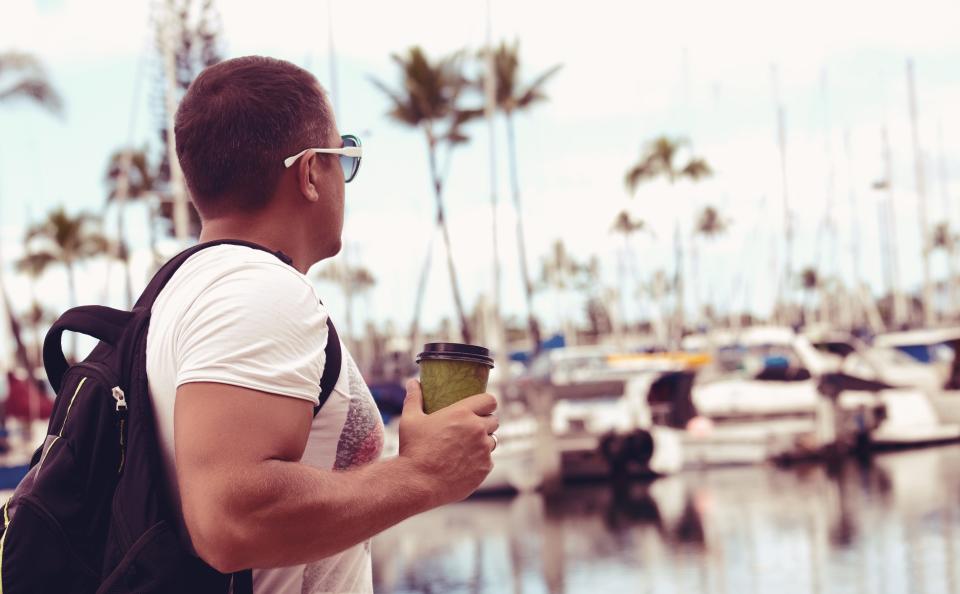 Man walking with coffee in Ala Wai Yacht Harbor in Honolulu on Oahu Island, Hawaii.