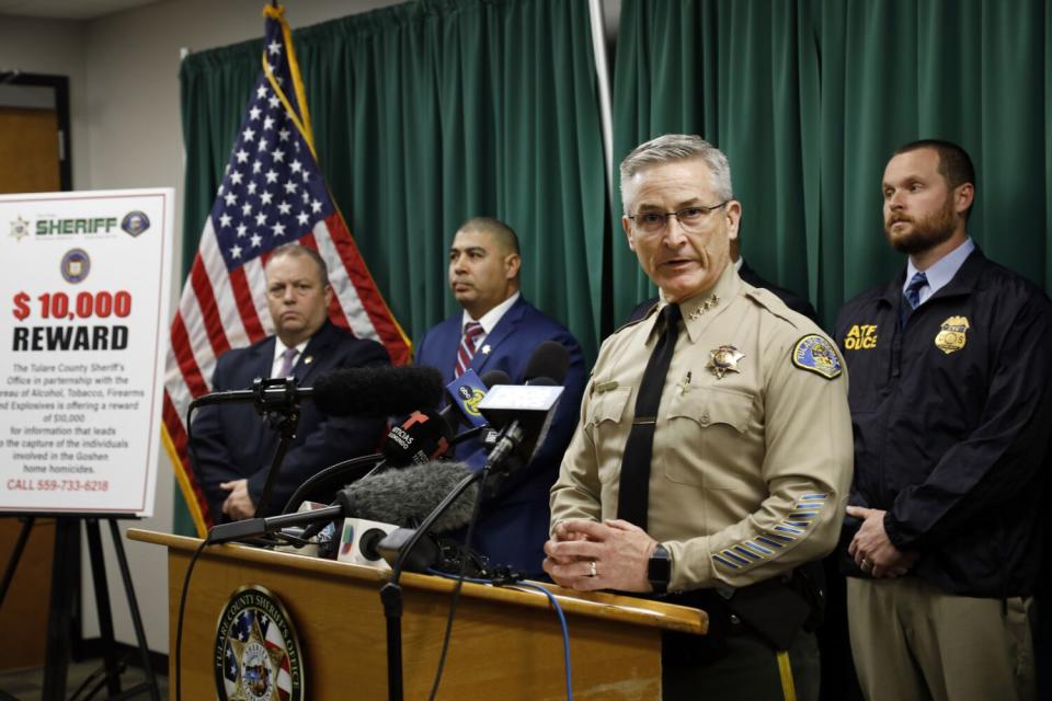 A uniformed man talks at a lectern with three men behind him.