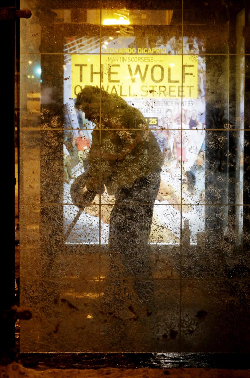 A man clean the snow at a bus stop in downtown Chicago, Wednesday, Jan. 1, 2014. As much as 9 inches of snow has fallen in some parts of the Chicago area since New Year's Eve, and a second wave is expected to dump several more inches by Thursday. (AP Photo/Nam Y. Huh)