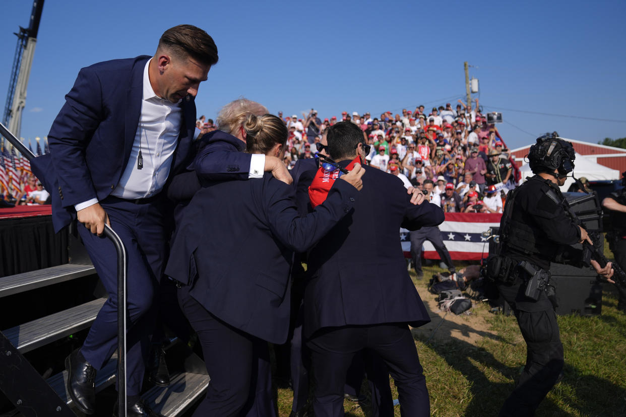 Secret Service agents surround Trump as they whisk him off the stage.