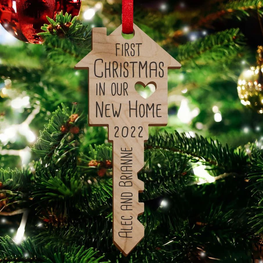 Our First Home 2022 Ornament. Key shaped ornament with personalized writing hanging on a tree.