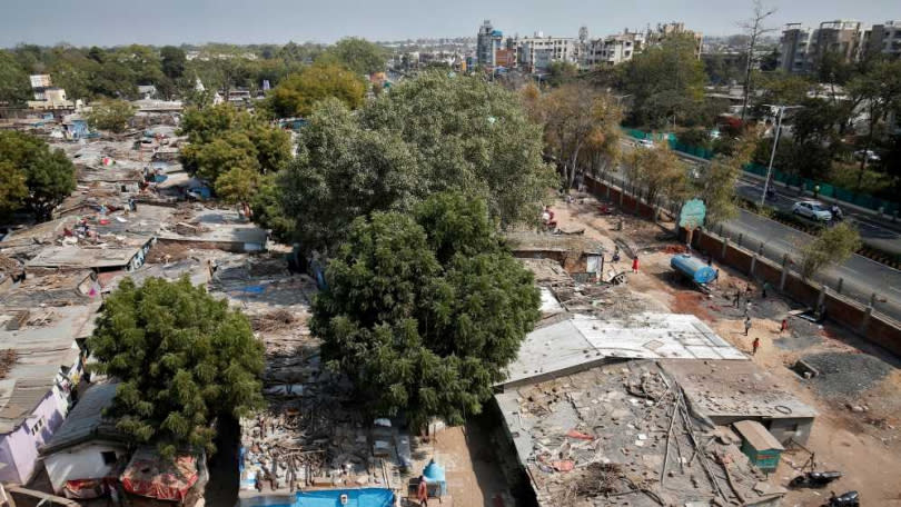 在川普訪問之前，印度工人在貧民窟前修建磚牆。 （圖／Reuters）