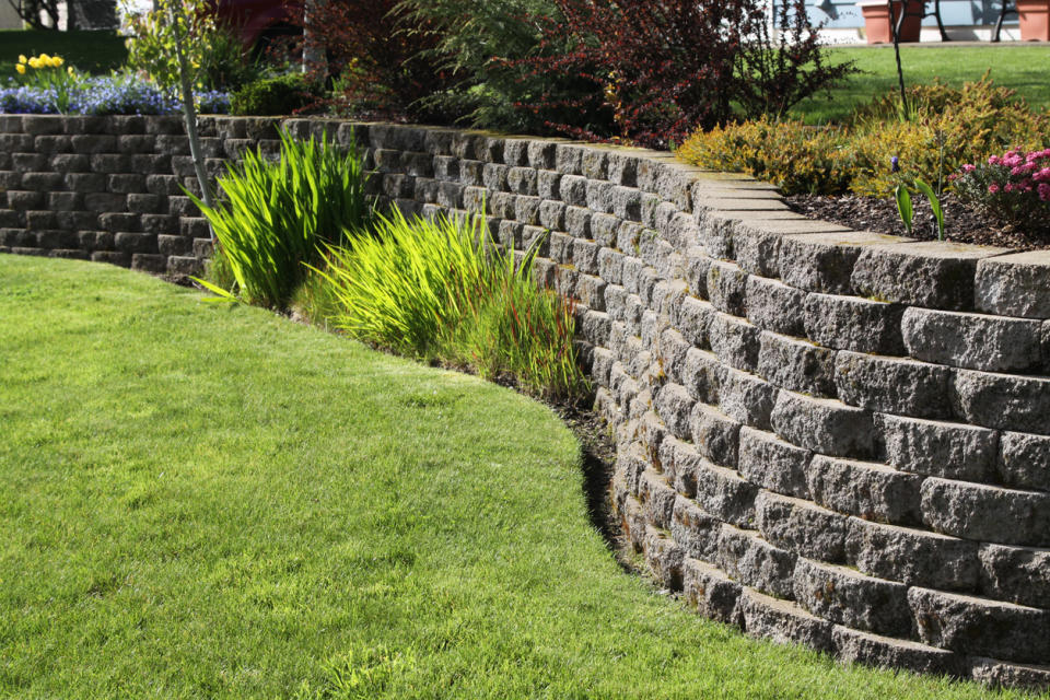 A view of a railroad tie retaining wall against a verdant backdrop.