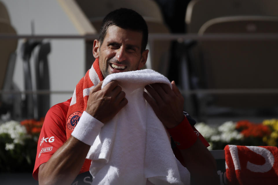 Serbia's Novak Djokovic laughs when switching ends in the second round match of the French Open tennis tournament against Lithuania's Ricardas Berankis at the Roland Garros stadium in Paris, France, Thursday, Oct. 1, 2020. (AP Photo/Alessandra Tarantino)