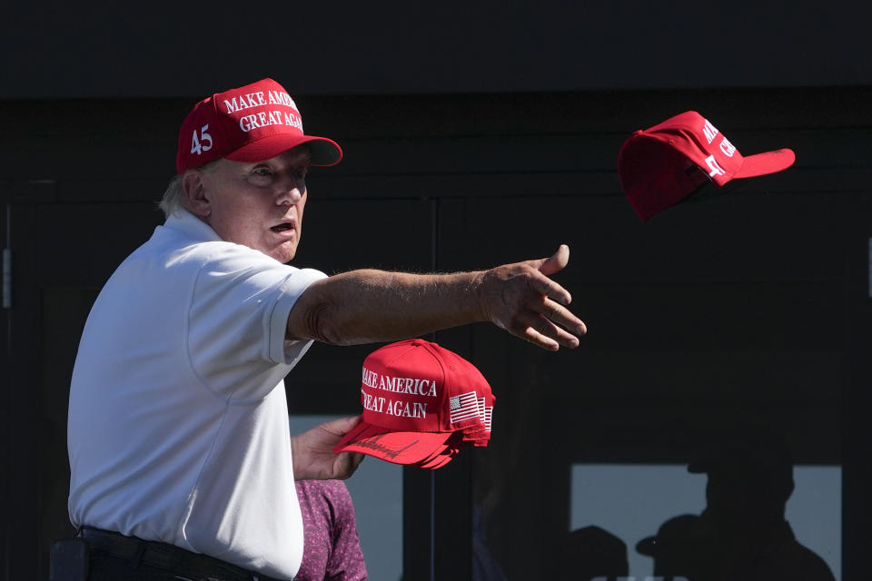 FILE - Former President Donald Trump throws autographed hats to the crowd during the final round of the Bedminster Invitational LIV Golf tournament in Bedminster, N.J., Sunday, Aug. 13, 2023. He's a criminal defendant, a businessman and a politician. But to his most loyal supporters, Donald Trump will always be Mr. President. When it comes to signaling our political loyalities, language can be just as telling as a MAGA cap, offering a simple by subtle reminder of the false election claims that continue to reverberate online, as well as the polarization that has gripped our politics and divided our people.(AP Photo/Seth Wenig, File)