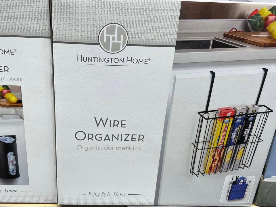 Gray boxes with Huntington Home label and wire organizer labels. A picture of a wire over-the-door hanger containing plastic wrap is on the box