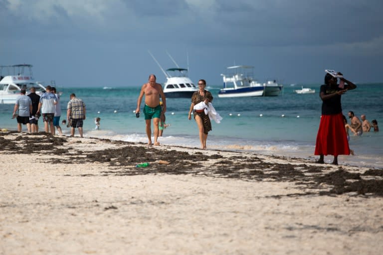 Turistas disfrutan de una caminata por una playa en Punta Cana en República Dominicana, el 7 de enero de 2022. (AFP/Erika SANTELICES)