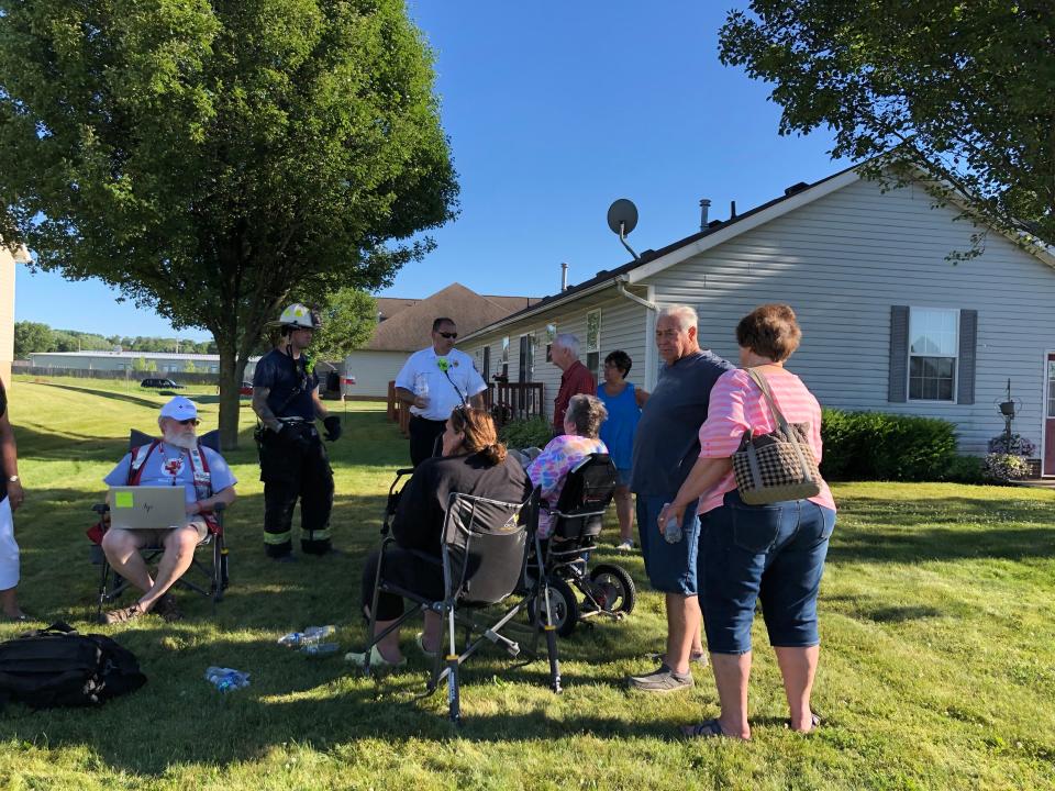 Massillon Fire Chief Matt Heck, in the white shirt, speaks Thursday evening with Ron Baker, in the red shirt, and his wife Sandy Baker, in the wheelchair about recovering their possessions in their smoke-damaged duplex unit on Evangel Ave. NW.