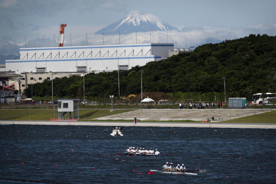 FILE - In this June 16, 2019, file photo, rowers prepare for a test run at the Sea Forest Waterway, a venue for rowing at the Tokyo 2020 Olympics, as Mount Fuji is visible in the distance in Tokyo. Scandals and rising costs have not deterred interest in Japan in the Tokyo Olympic. They open in a year with unprecedented ticket demand. (AP Photo/Jae C. Hong, File)