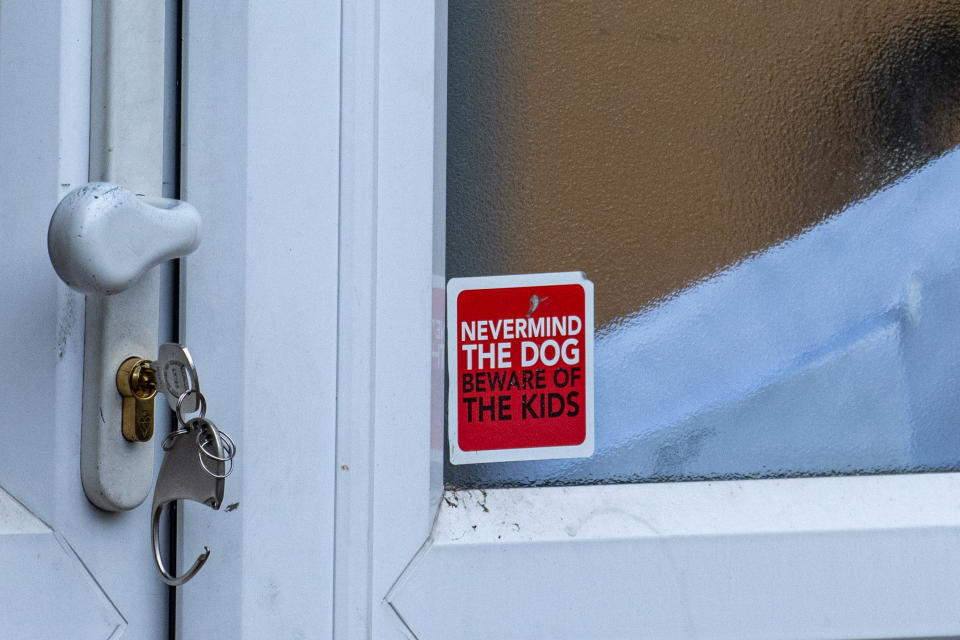 A sign on the door of a house where a woman was killed by her two XL Bully dogs. (SWNS)