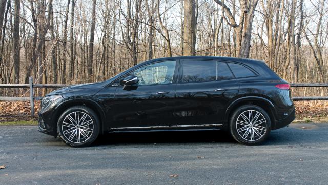 A black 2023 Mercedes-Benz EQS SUV seen from a side view with trees in the background.