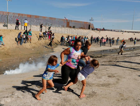 Maria Meza, a 40-year-old woman from Honduras traveling as part of a caravan of thousands from Central America to the United States, runs away from tear gas with her 5-year-old twin daughters Saira Mejia Meza and Cheili Mejia Meza. (Photo: Reuters)