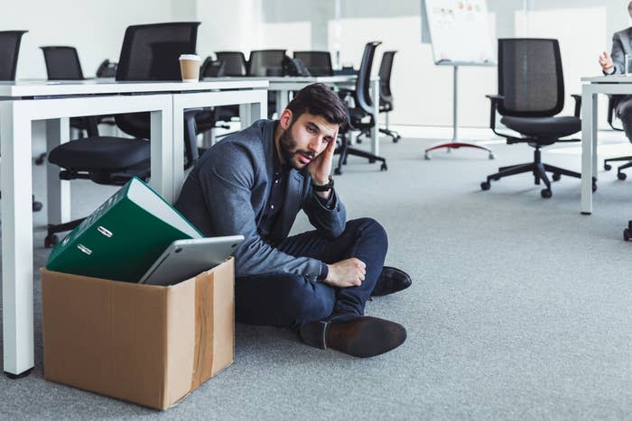 A worker sitting next to a box of his items