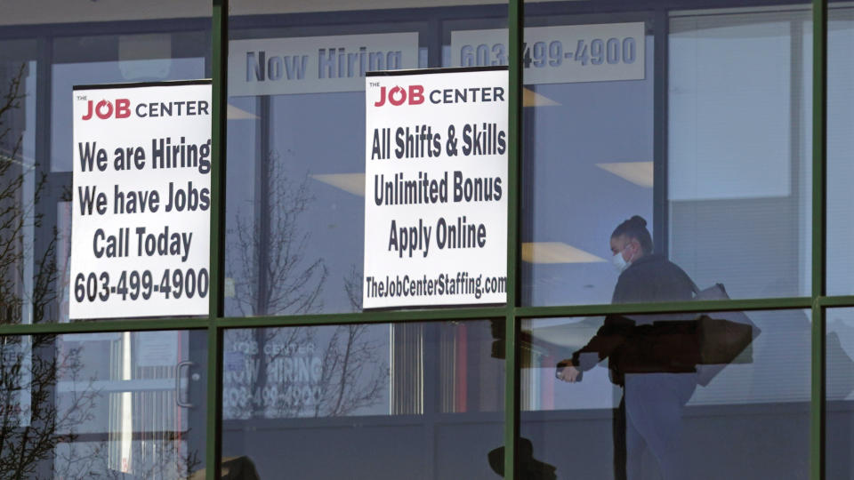 A woman, wearing a protective mask due to the COVID-19 virus outbreak, walks past the signs of an employment agency, Tuesday, March 2, 2021, in Manchester, N.H. After a year of ghostly airports, empty sports stadiums and constant Zoom meetings, growing evidence suggests that the economy is strengthening. Hiring picked up in February 2021. Business restrictions have eased as the pace of viral infections has ebbed. Yet the economy remains far from normal. (AP Photo/Charles Krupa)