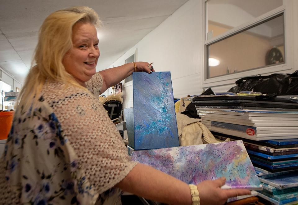 Showing samples of her artwork, is Karen McDonald, inside the enclosed deck of her mobile home in Falls Township, on Monday, Nov. 8, 2021.