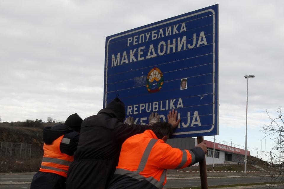 Workers remove a road sign that reads ''Republic of Macedonia'' in the southern border with Greece, near Gevgelija, Wednesday, Feb. 13, 2019. The small Balkan country of Macedonia officially changed its name Tuesday by adding a geographic designation that ends a decades-old dispute with neighboring Greece and secures its entry into NATO. (AP Photo/Boris Grdanoski)