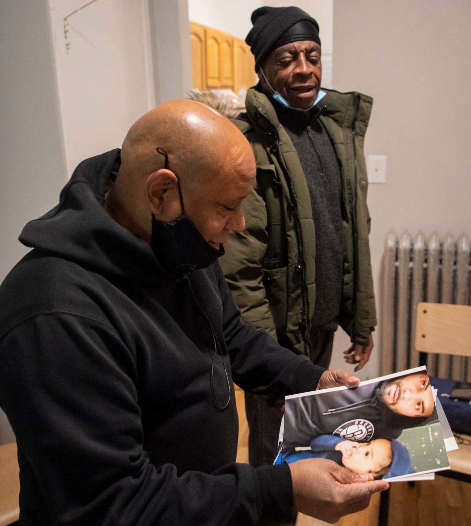 Shams DaBaron (left) and Larry Thomas (right) look at photos of Thomas' family in his new home in West Harlem on Dec. 6, 2020.