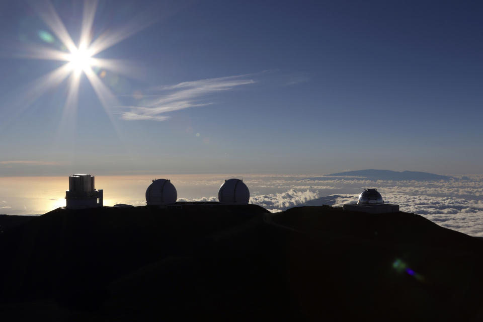 FILE - In this Sunday, July 14, 2019, file photo, the sun sets behind telescopes at the summit of Mauna Kea in Hawaii. The National Science Foundation has launched an informal outreach to Hawaii about possible funding efforts for the stalled Thirty Meter Telescope project. The Honolulu Star-Advertiser reported the effort by the nation's top funder of basic research could lead to a huge influx of cash for the astronomy project on Mauna Kea with an estimated cost of $2.4 billion. AP Photo/Caleb Jones, File)