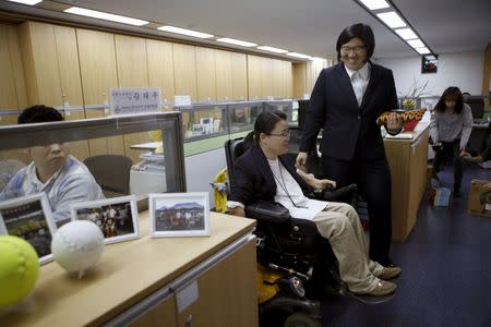 Kim So-young, a former gymnast who was paralysed from the neck down at 16 after falling off the parallel bars while training, talks to former Olympic gold medalist Jang Mi-ran (R) at her office in Seoul, South Korea, October 23, 2015. REUTERS/Kim Hong-Ji