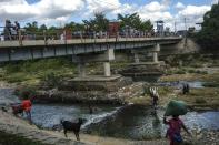 Men bathe in the Massacre River on the border between Dominican Republic and Haiti, in Ouanaminthe, Dominican Republic, Friday, Nov. 19, 2021. As the rest of the world closes its doors to Haitian migrants, the country that shares an island with Haiti also is cracking down in a way that human rights activists say hasn’t been seen in decades. (AP Photo/Matias Delacroix)