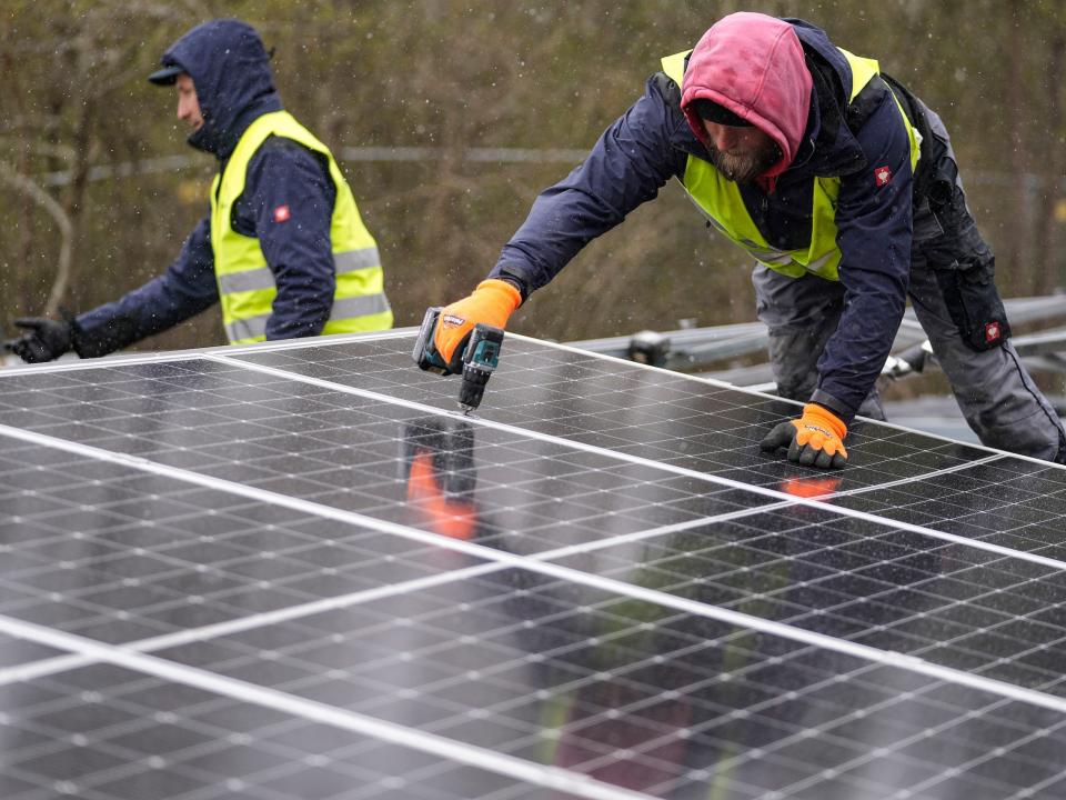 workers install solar panels using a drill