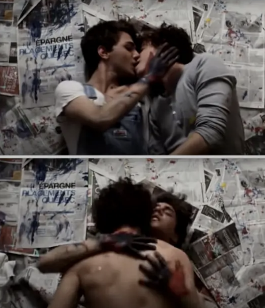 Two people are passionately kissing and embracing on what appears to be a paint-splattered floor, surrounded by newspapers and posters