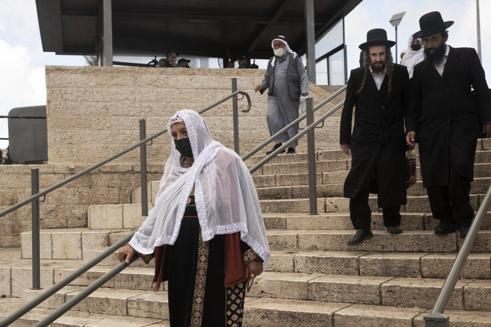 A woman in traditional Palestinian dress walks towards the Damascus Gate to the Old City of Jerusalem for prayers at the Al Aqsa Mosque compound marking Moulid al-Nabi, the birthday of the Muslim Prophet Muhammad, Tuesday, Oct. 19, 2021. (AP Photo/Maya Alleruzzo)