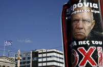 A referendum campaign poster depicting German Finance Minister Wolfgang Schaeuble is seen as a Greek national flag flutters atop the Athens Academy, Greece, July 2, 2015. REUTERS/Alkis Konstantinidis