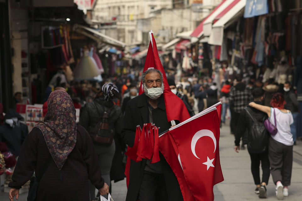 FILE - In this Monday, March 22, 2021 file photo, a vendor offers Turkish flags for sale at an open market in Istanbul. Turkish President Recep Tayyip Erdogan urged investor confidence in Turkey's economy on Wednesday, March 24, 2021, days after he fired his third central bank governor in less than two years, shaking trust in the country and causing a market upheaval. (AP Photo/Emrah Gurel, File)