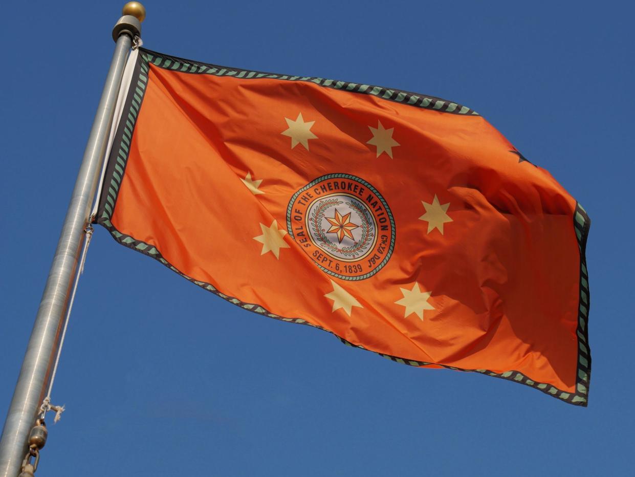 Flag of the Cherokee Indian nation of Oklahoma waving unfurled with blue skies in the background