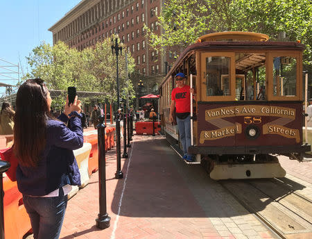 Tourists take pictures of an immobile cable car during a power cut in downtown San Francisco, California, U.S. April 21, 2017. REUTERS/Alexandria Sage