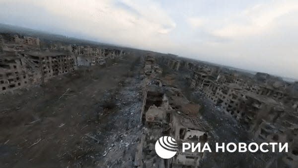 A sweeping aerial view of destroyed buildings on a brown landscape.