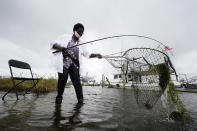 Minnie Lewis fishes for crabs before the wind and waves kick up, in Chalmette, La., Wednesday, Oct. 28, 2020. Hurricane Zeta is expected to make landfall this afternoon as a category 2 storm. (AP Photo/Gerald Herbert)