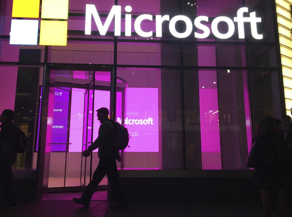 FILE - In this Nov. 10, 2016, file photo, people walk past a Microsoft office in New York. For the first time in two years for many people, the American workplace is transforming into something that resembles pre-pandemic days. The U.S. has since seen COVID-19 infections and hospitalizations plummet. Cases have plunged from 455,000 a day two weeks ago to 150,000 on Monday, Feb. 14, 2022. (AP Photo/Swayne B. Hall, File)