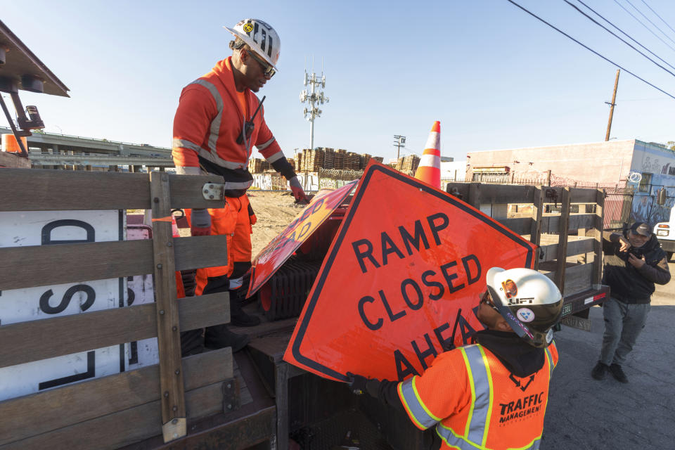 Traffic management workers select signs to close up a ramp around the Interstate 10 freeway in Los Angeles, Saturday, Dec. 9, 2023. (AP Photo/Damian Dovarganes)