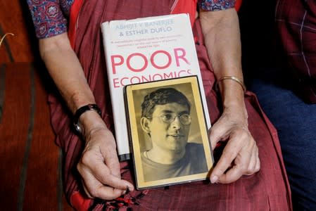 Nirmala Banerjee, mother of Abhijit Banerjee, one of the winners of 2019 Nobel Economics Prize, holds his portrait and one of his books, as she speaks to media at her house in Kolkata