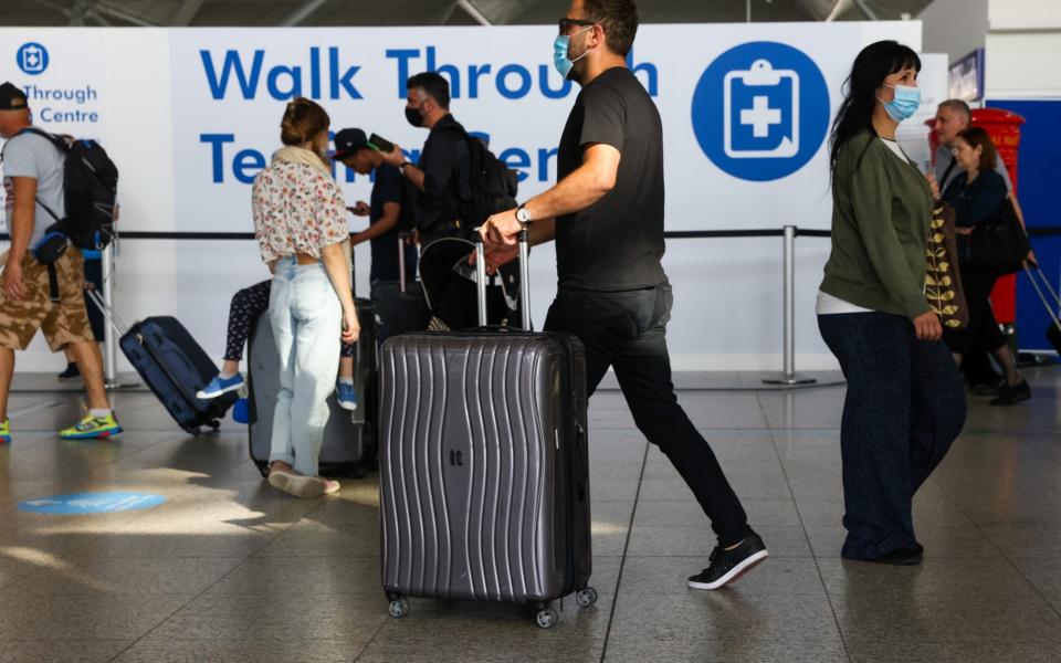 Passengers pass a Covid-19 testing centre sign at London Stansted Airport - Chris Ratcliffe/Bloomberg