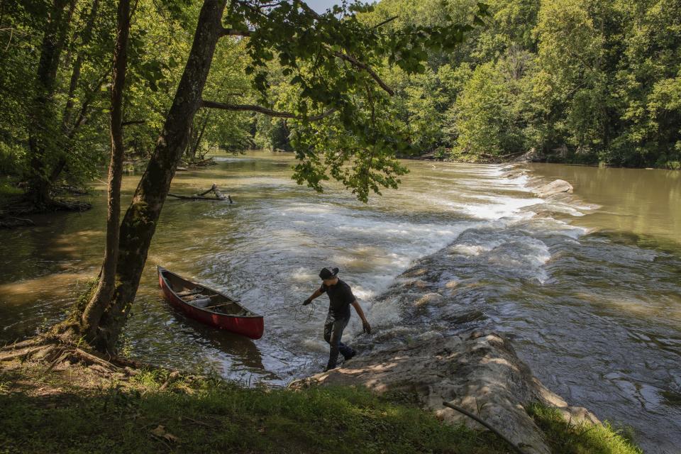 This July 26, 2019 photo provided by the Nature conservancy shows a StreamSweepers employee pulls a canoe to shore on the Clinch River, Va. The Cumberland Forest Project protects 253,000 acres of Appalachian forest in Tennessee, Kentucky, and Virginia and is one of TNC's largest-ever conservation efforts in the eastern United States. StreamSweepers is a not for profit river maintenance and restoration service, staffed by young adults from Central Virginia. StreamSweepers assess the ecological health of rivers in the Piedmont portion of the state and remove small to large trash items from the river bed and banks. (Travis Dove/The Nature Conservancy via AP)