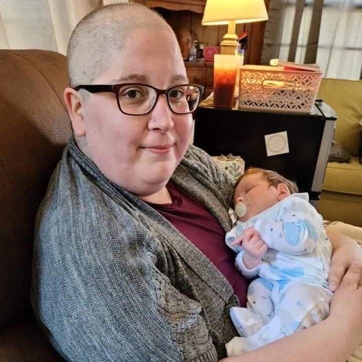 Stephanie Clark holding her newborn nephew in 2021 with bald head from chemo