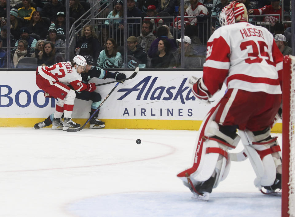 Detroit Red Wings defenseman Moritz Seider (53) collides with Seattle Kraken right wing Jordan Eberle as Red Wings goaltender Ville Husso (35) watches during the second period of an NHL hockey game Saturday, Feb. 18, 2023, in Seattle. (AP Photo/ Lindsey Wasson)