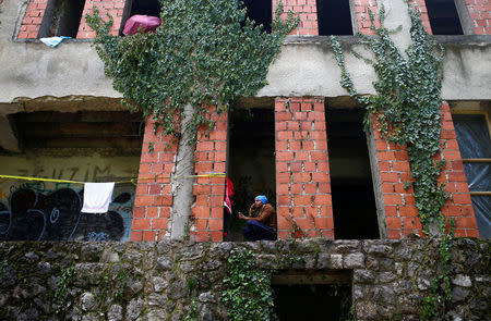 Migrants sit outside a dorm destroyed during the Bosnian 1992-1995 war, in Bihac, Bosnia and Herzegovina May 11, 2018. REUTERS/Dado Ruvic