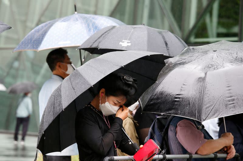 A woman mourns as the hearse carrying late Seoul Mayor Park Won-soon leaves Seoul City Hall Plaza after his funeral, in Seoul